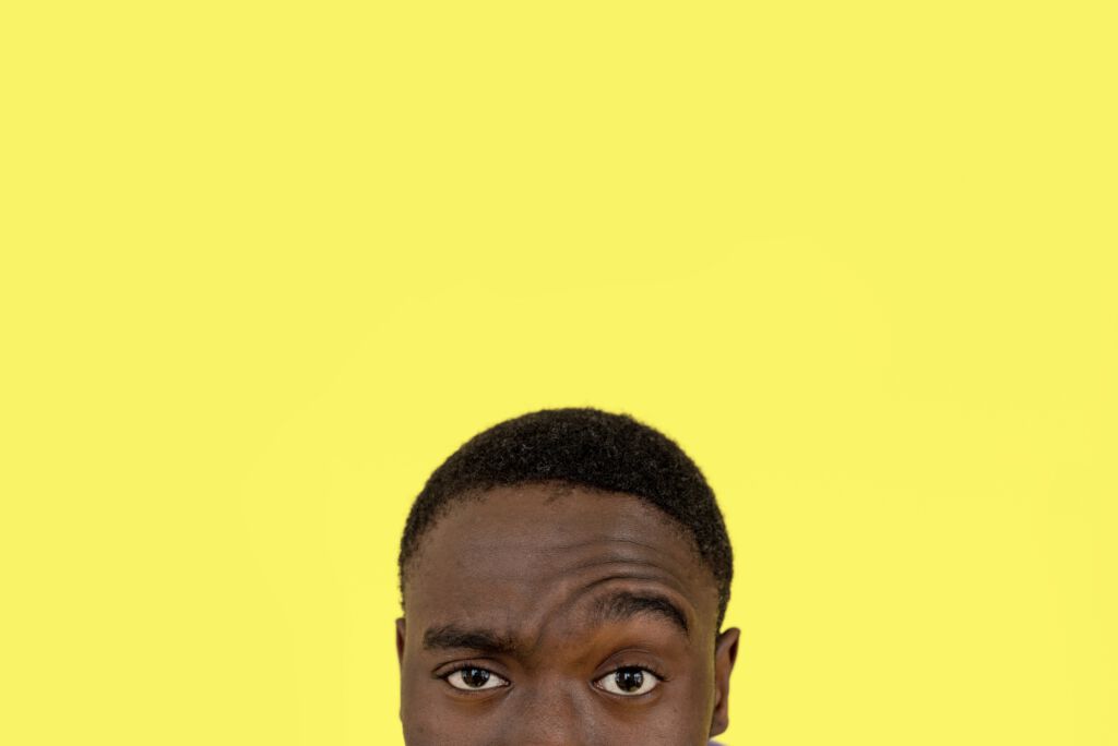 An inquisitive young man with a bright yellow background - FANCLB For Creators